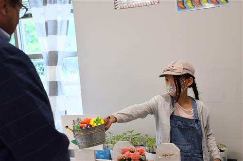 Board member Travis Cummings talking with girl dressed as a farmer at a market 